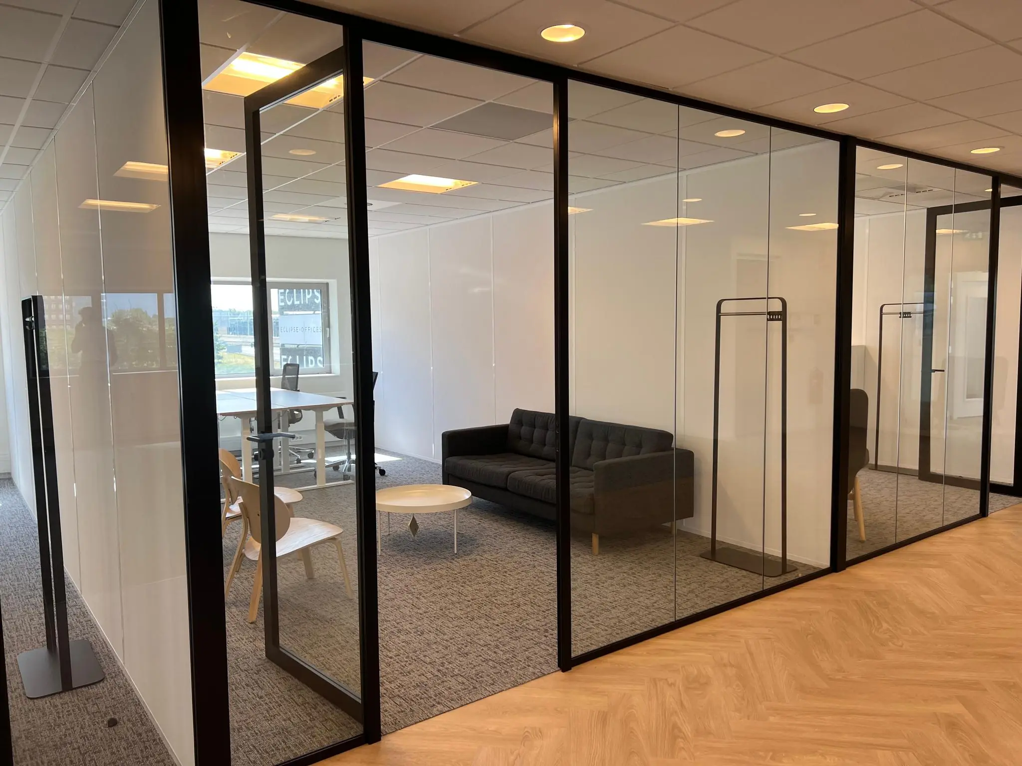 Moderne kantoorruimte in Rivium Quadrant met glazen wanden, een vergadertafel en een zithoek met zwarte bank.